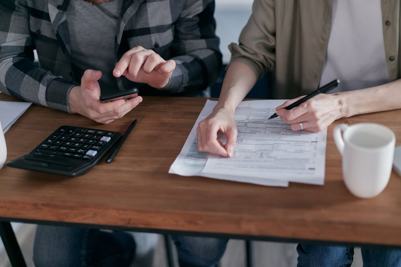 A freelancer checking income on a phone next to tax paperwork