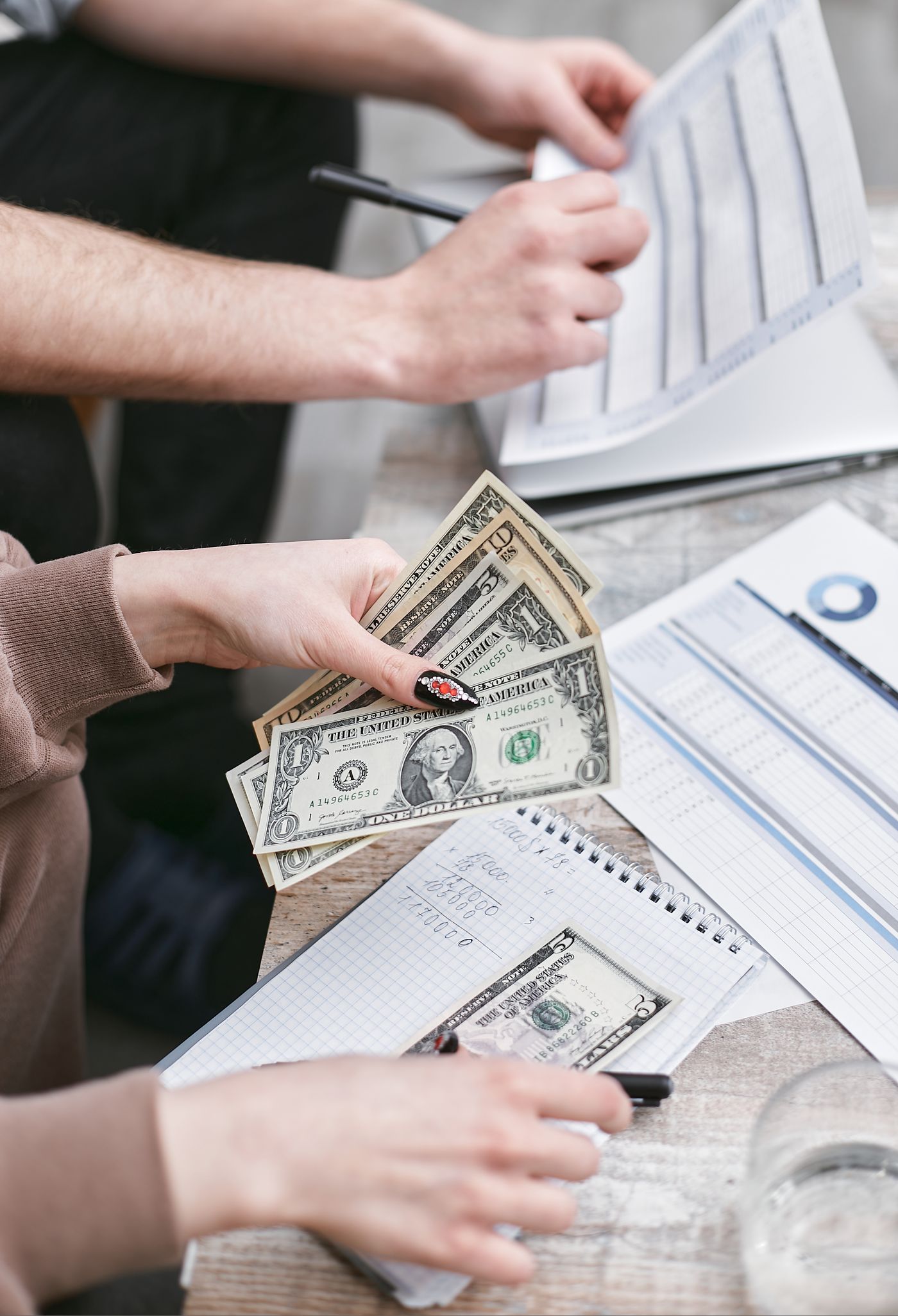 A freelancer counting out a cash payment over a notebook of figures